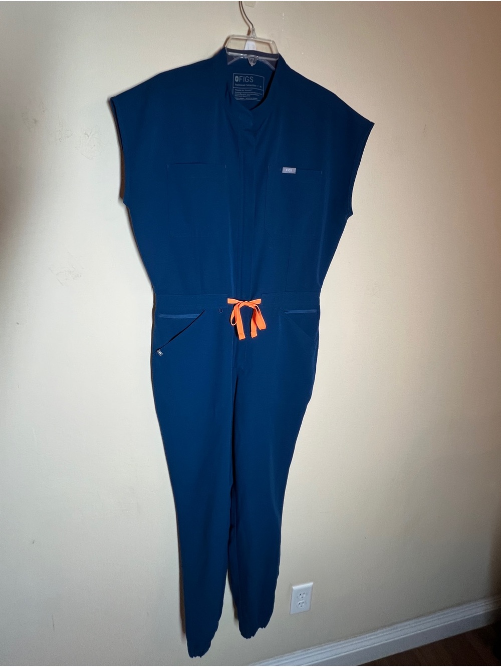 Figs Rafaela Jogger Scrub Jumpsuit Blue with orange tie.